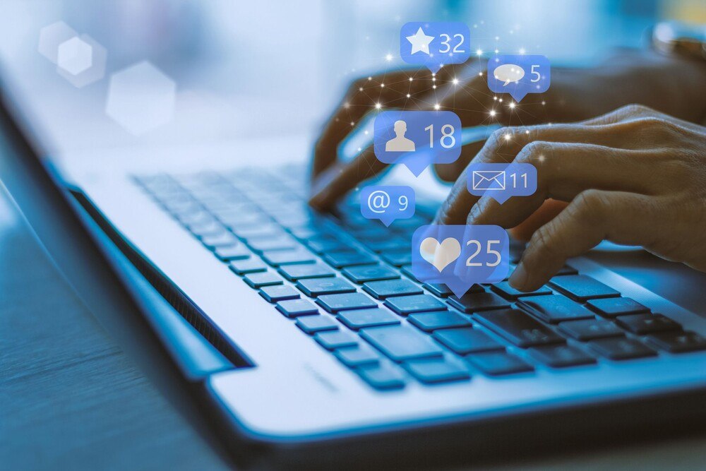 © Getty Images / Urupong Frauenhände am Laptop mit Social Media Icons