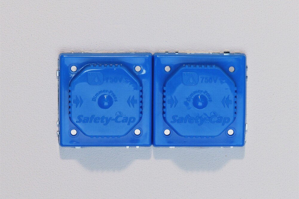 © www.safety-cap.de Abgedeckte Doppelsteckdose mit zwei Safety-Caps.