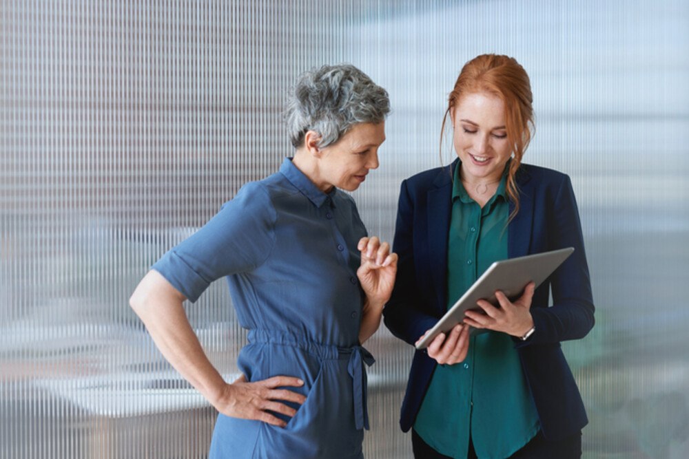 © PeopleImages iStock Getty Images Plus Zwei Frauen, eine hält einen Tablet PC