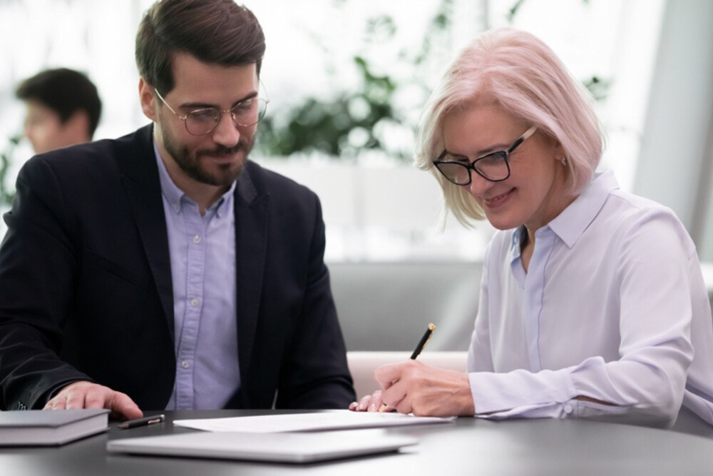 © fizkes iStock Getty Image Plus eine ältere Dame und ein Herr sprechen über Papiere am Tisch