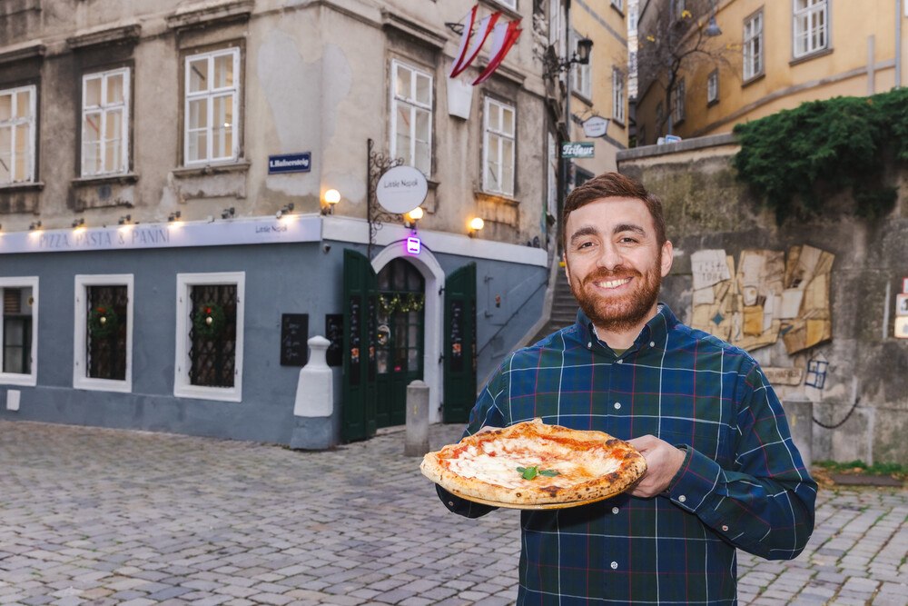 © Robin Consult/Fellner Der Eigentümer mit Pizza in der Hand vor dem Restaurant