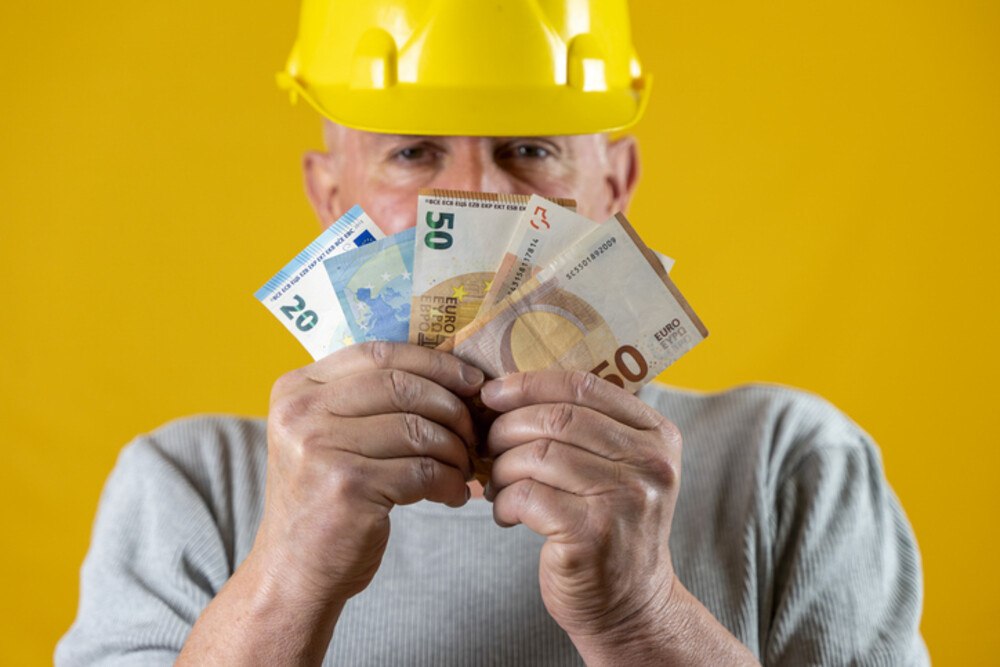 © nautiluz56 iStock Getty Images Plus Bauarbeiter hält Bargeld in der Hand