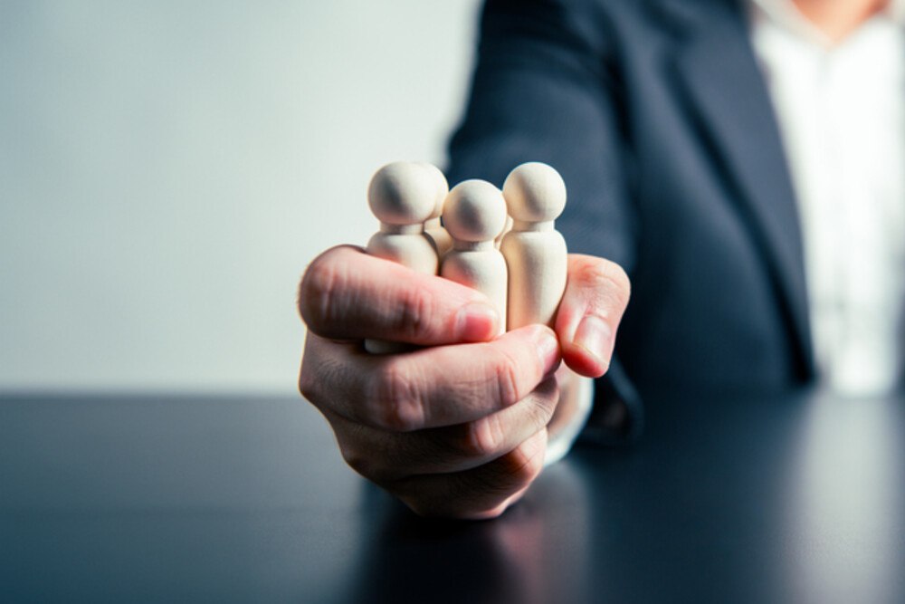 © Shutter2U iStock / Getty Images Plus Geschäftsperson hält Figuren fest in der Hand