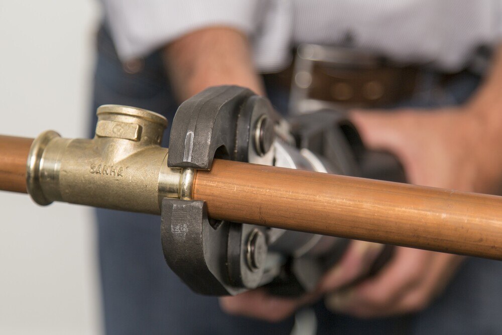 © SANHA GmbH & Co. KG, Essen
Fittings aus Siliziumbronze werden gepresst.
Ein Mann hält eine Rohrzange und arbeitet an einem Verbindungstück eines Kupferrohrs.