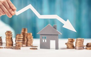 ein Pfeil, der nach unten zeigt, über einem Holzhaus neben Geldmünzen