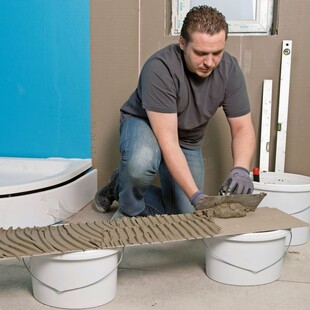 © Murexin Der Arbeiter bringt den Klebemörtel mit einer Kammkelle vollflächig auf der Trägerplatt auf