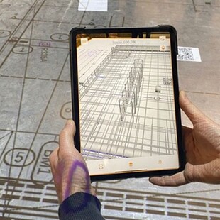 © Schöck Bauteile GmbH Arbeiter sieht durch das Tablet und direkt am Betonteil die vorgegebenen Linien und Angaben von "Chekker" .