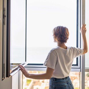 © getty images/ dangrytsku Frau öffnet Fenster zum Lüften eines Raumes