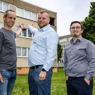 © Vonovia / Karsten Socher Fotografie Henry Flade, Mitarbeiter der Firma Walter Fenster und Türen, Matthias Koch, wissenschaftlicher Mitarbeiter am Institut für Werkstofftechnik der Universität Kassel, und Martin Schottek, Referent Klimaneutraler Gebäudebestand bei Vonovia (v. li.), präsentieren den eingebauten Prototyp des neuen Solarfensters.