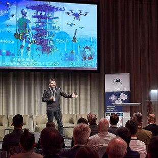 © Leo Hagen Mann spricht am Podium